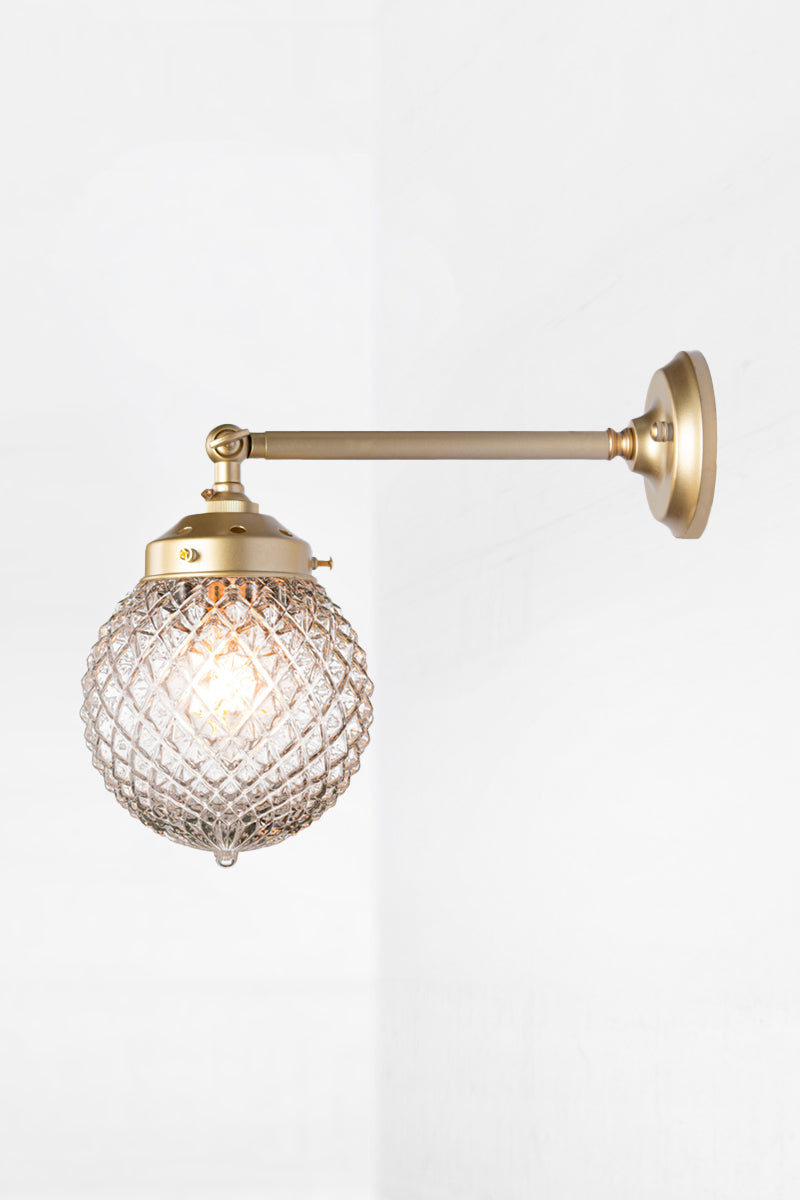 Vintage detailed, clear, glass orb shade on a long straigh wall sconce in gold/brass with a swivel lampholder. 