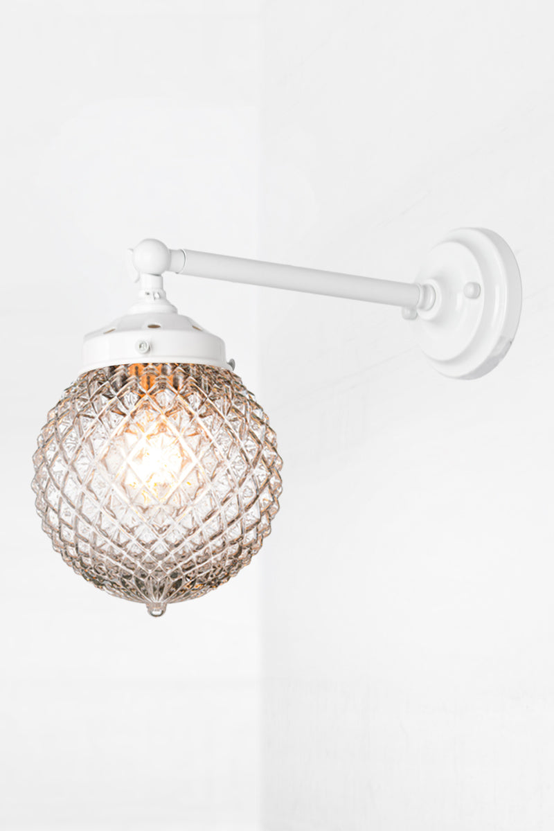 Vintage detailed, clear, glass orb shade on a long straigh wall sconce in white with a swivel lampholder. 