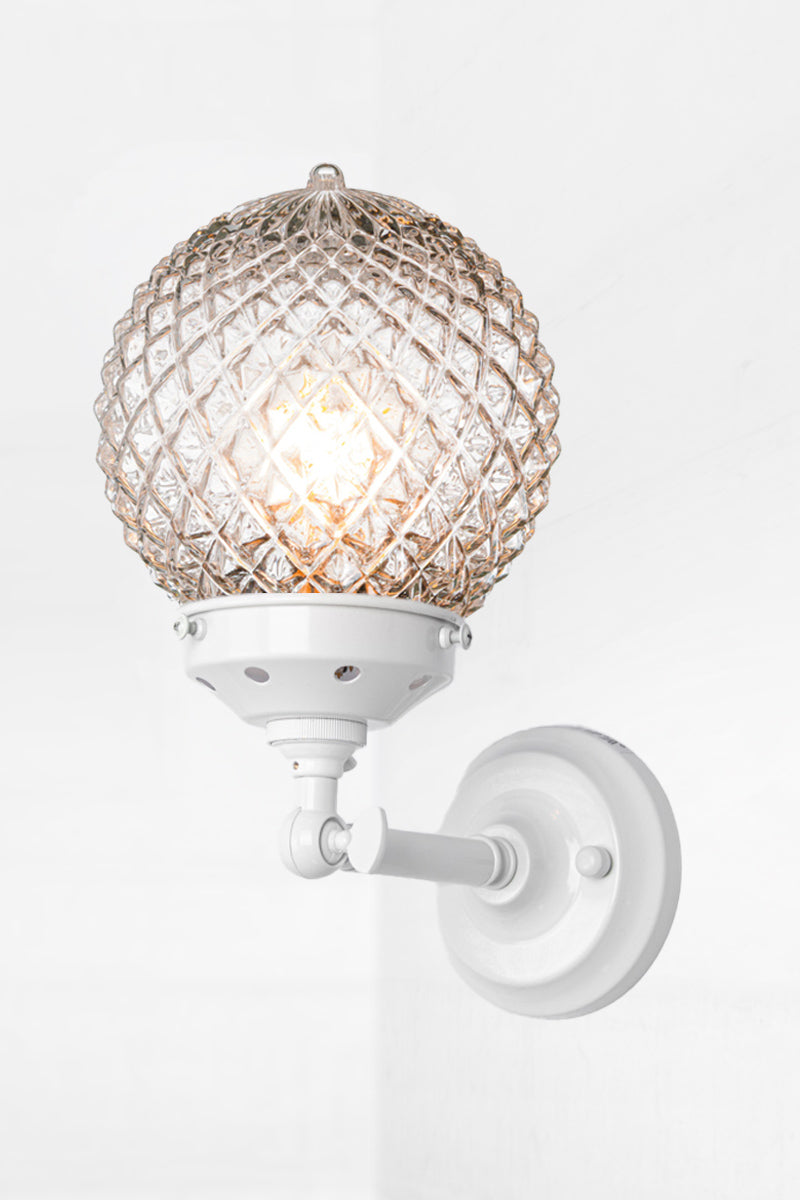 Vintage detailed, clear, glass orb shade on a short straigh wall sconce in white with a swivel lampholder. 