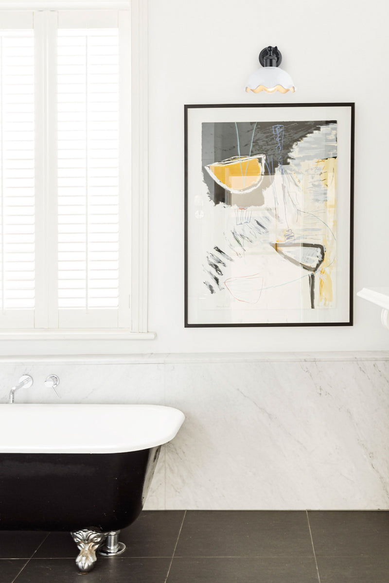 Ceramic shade in glossy whit on a mat blace wall sconce in a black and white bathroom. 