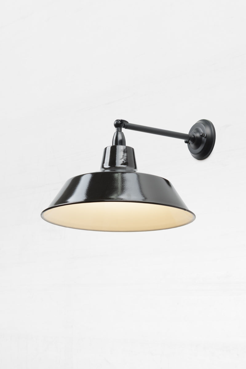 Long straight Arm outdoor wall sconce with a swivel lampholder and a black steel shade, showing the white inner. 