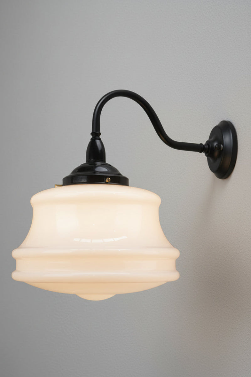 Side view of the large opal glass schoolhouse style shade on a black steel gooseneck wall sconce. 