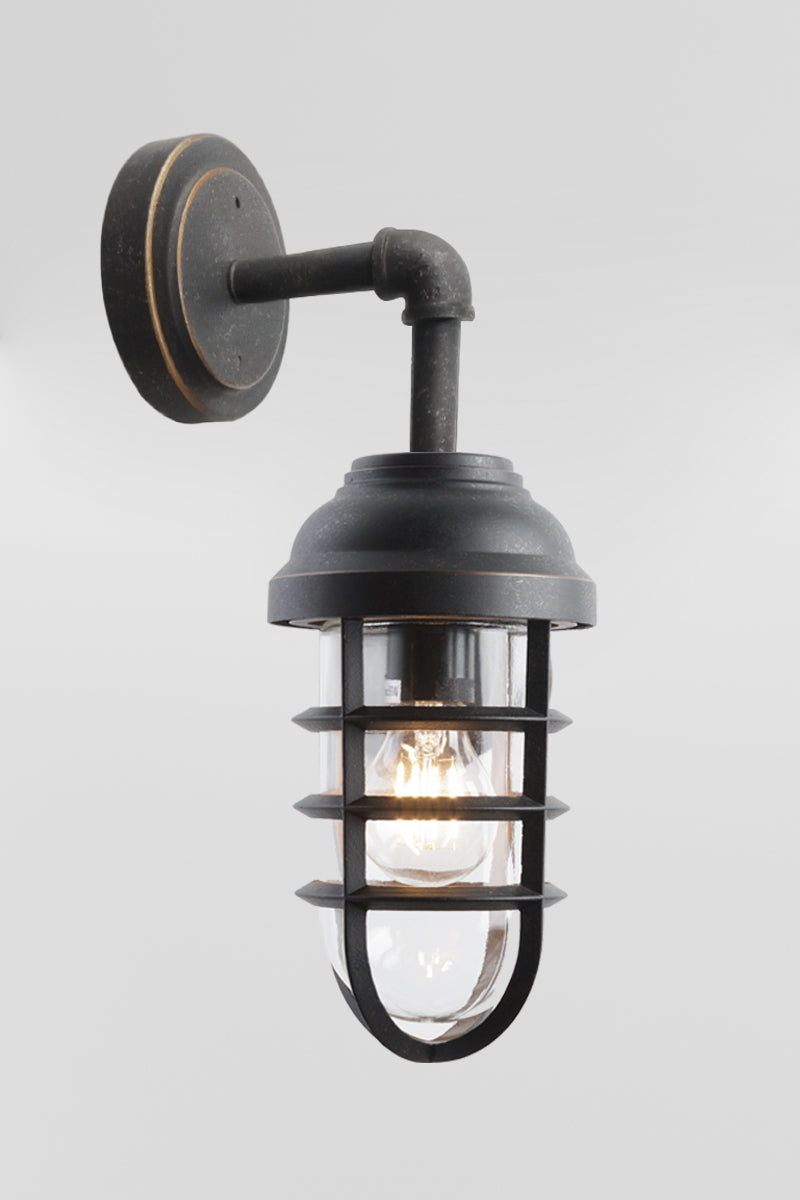 Antique Bronze finished steel outdoor wall light with cage detail and a lass shade. 