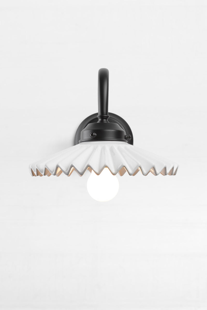 Front view of the black gooseneck wall arm with an integrated 2 and 1/4 cup, paired with a white ceramic shade. 