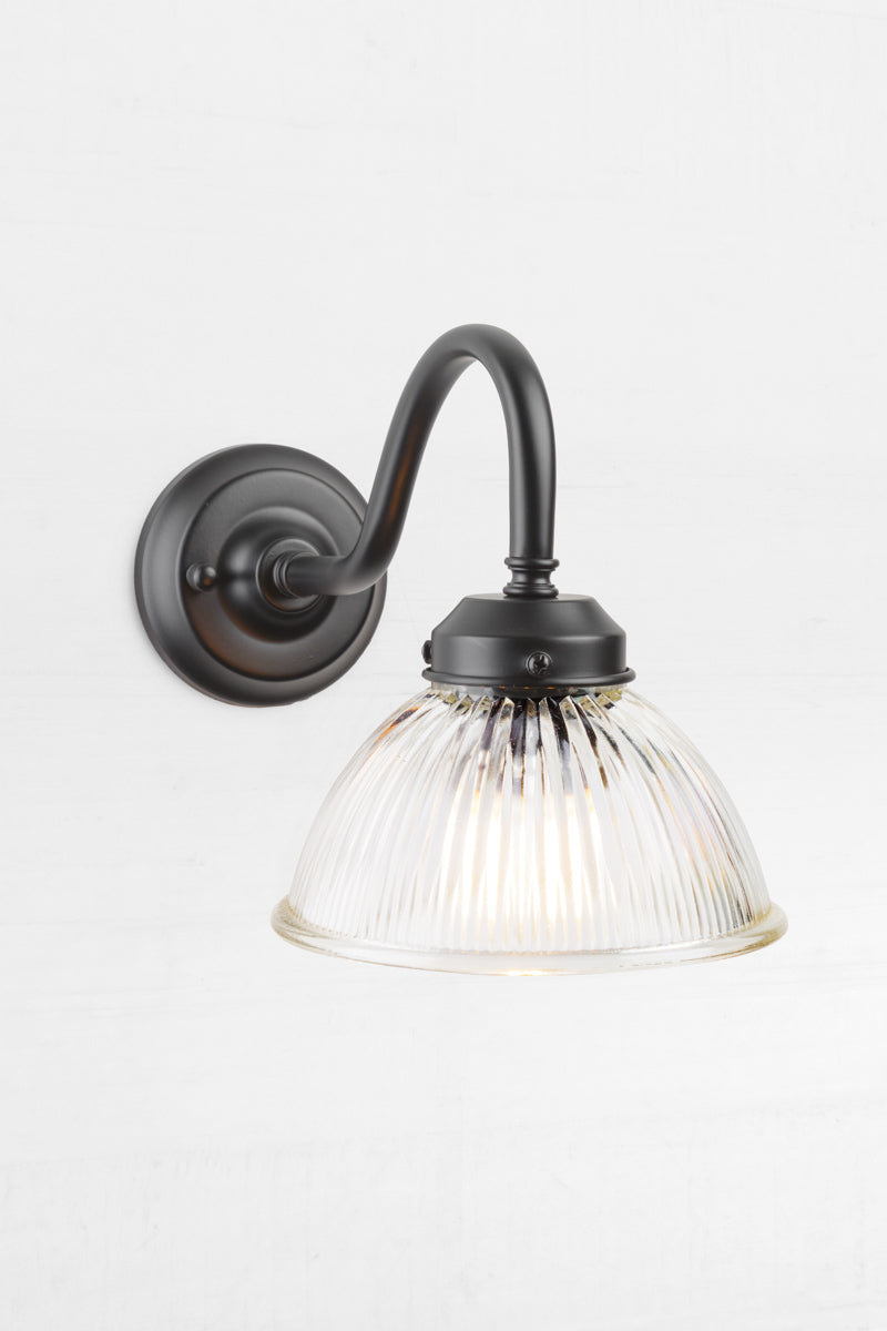 Level view of the black outdoor gooseneck wall light with a clear ribbed shade. 