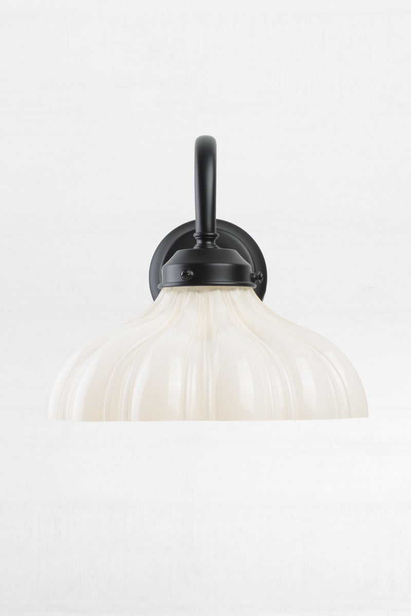 Black gooseneck wall sconce with integrated gallery, paired with an open opal glass shade with vintage detailing.