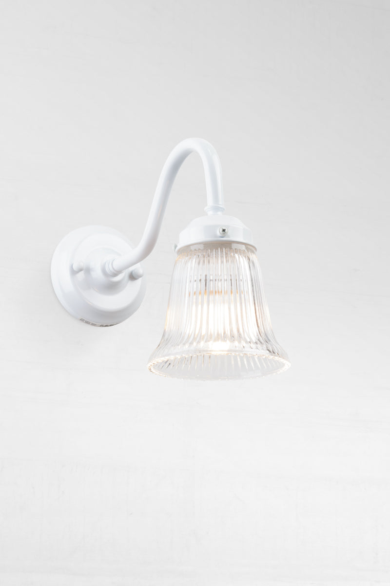 White gooseneck wall sconce with integrated gallery and a small clear ribbed shade. 
