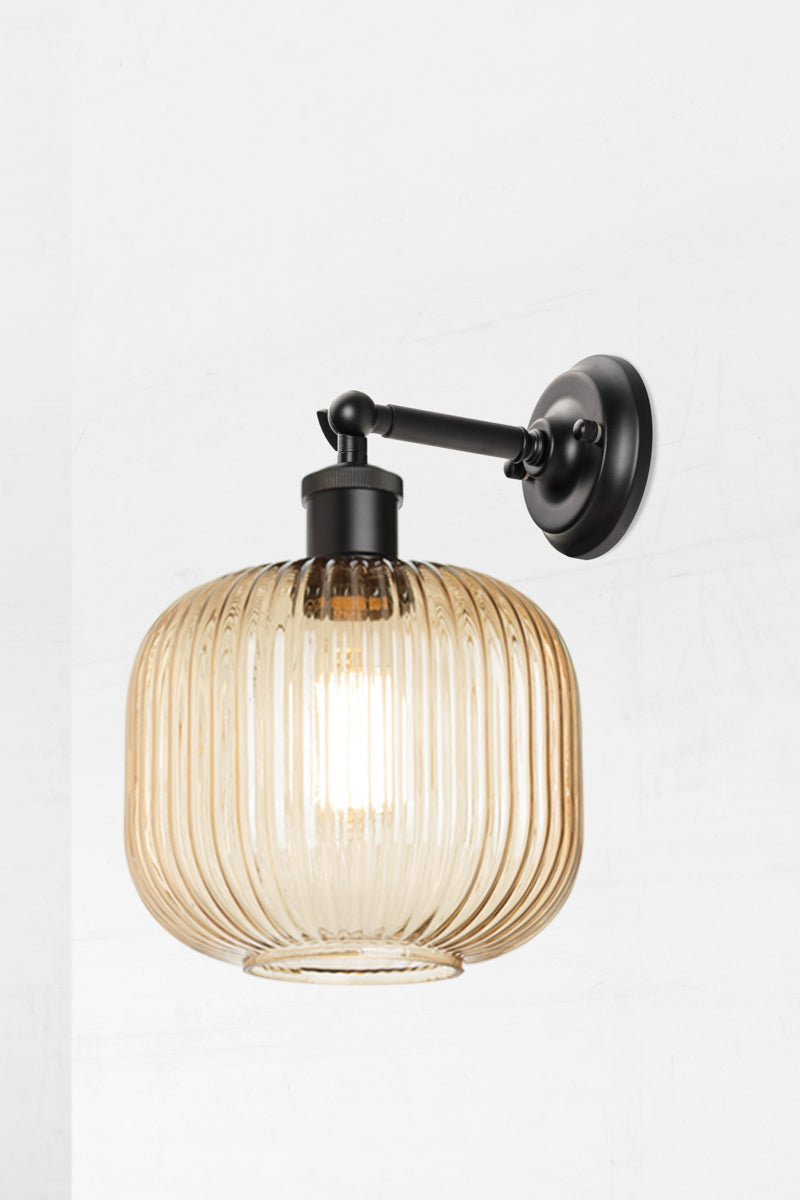 Black swivel wall sconce with short arm and a reeded glass shade in amber. 