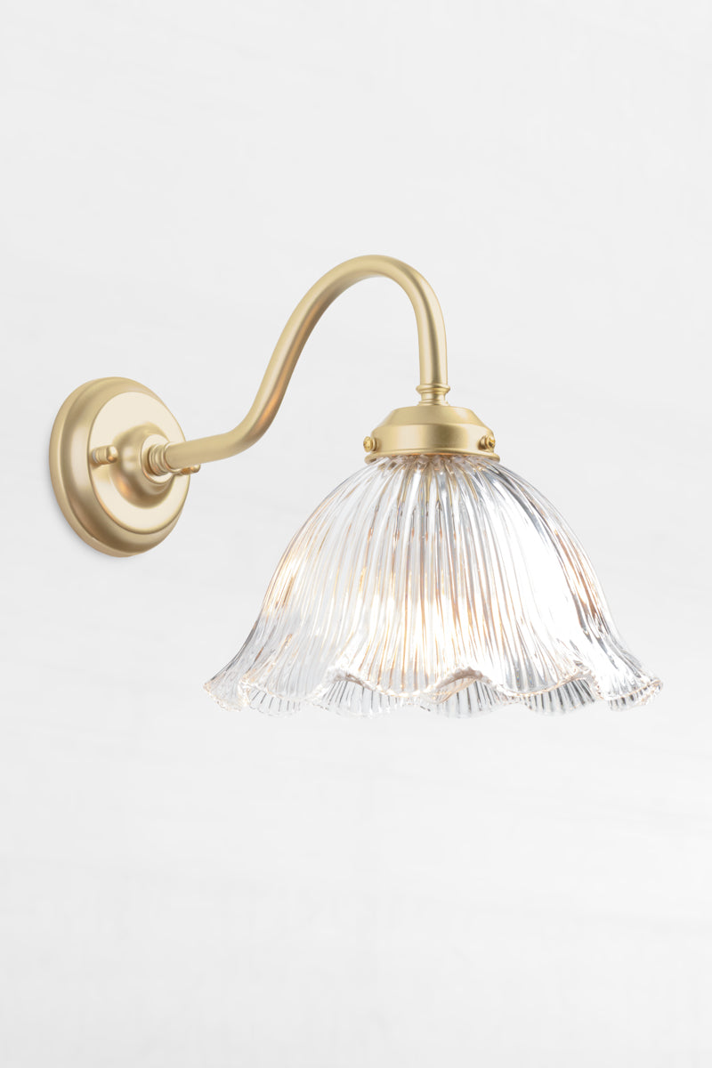 Gold/Brass gooseneck outdoor wall light with a clear glass shade that has a ribbed detiling and frill edge. 