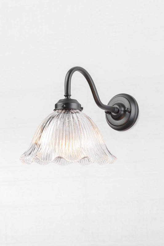 Black gooseneck outdoor wall light with a clear glass shade that has a ribbed detiling and frill edge. 