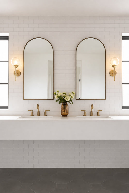 Two gold brass steel stem wall sconces paired with an opal glass ball shades, either side of double mirrors in a powderoom. 