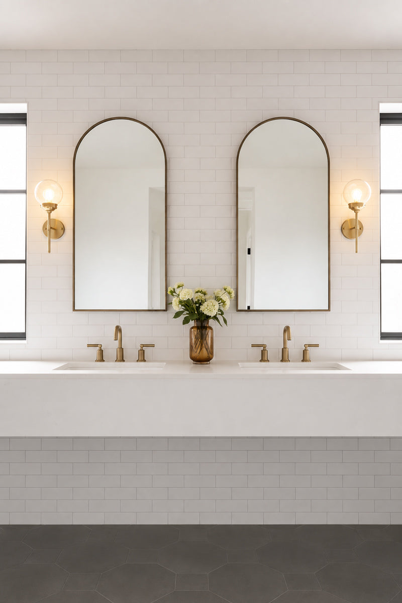 Two gold brass steel stem wall sconces paired with an opal glass ball shades, either side of double mirrors in a powderoom. 