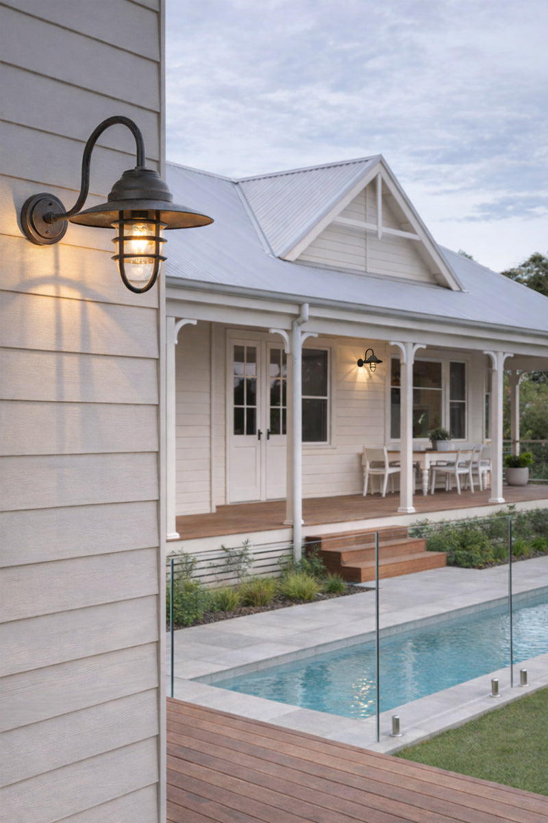 Gooseneck cage light in Antique Broze on a classic Australian weatherboard house next to a pool area. 
