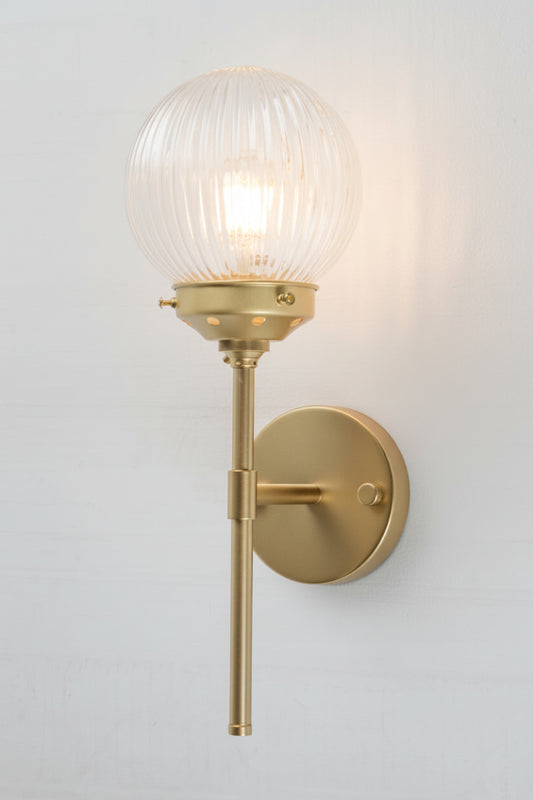 Gold/brass stem wall sconce paired with a clear reeded glass ball shade. 