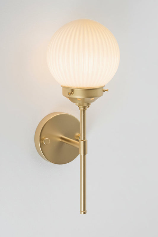 Gold/brass stem wall sconce paired with an opal reeded glass ball shade. 