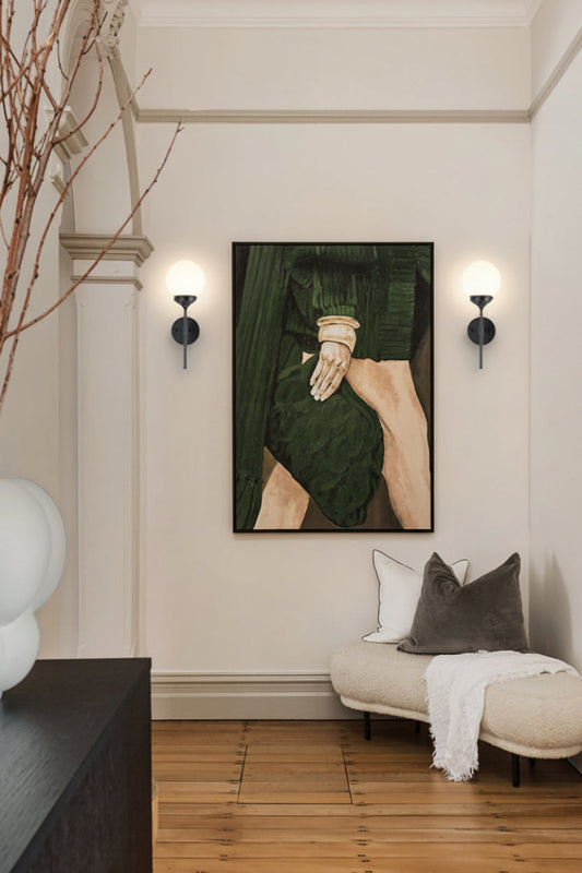 Two reeded glass ball shades on black wall stem sconces either side of beutiful modern art in a hallway with timber floors and fabric bench seat. 