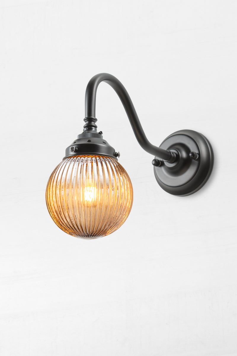 Black gooseneck wall sconce with a dark amber reeded glass ball shade. 