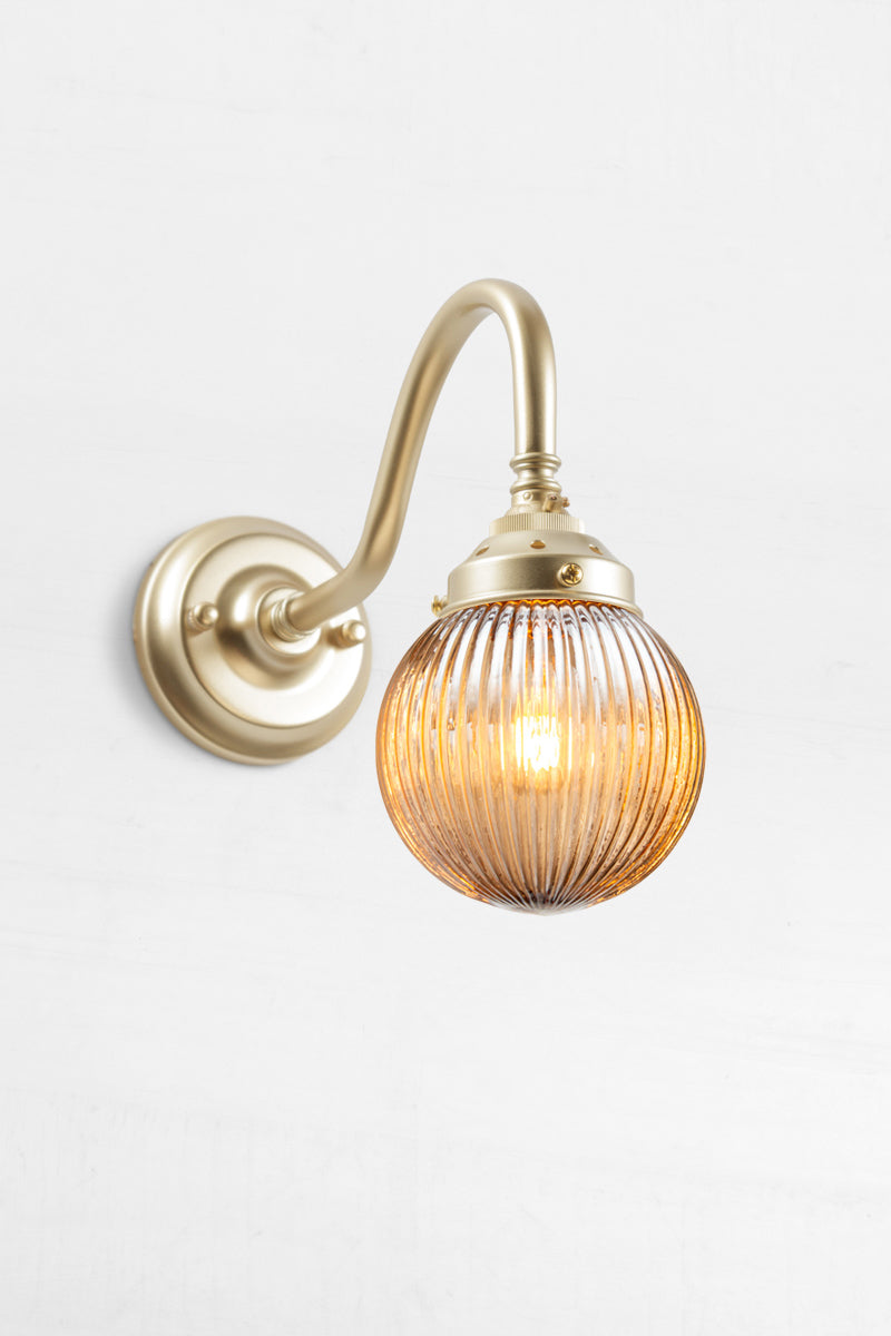 Gold/brass gooseneck wall sconce with a dark amber reeded glass ball shade. 