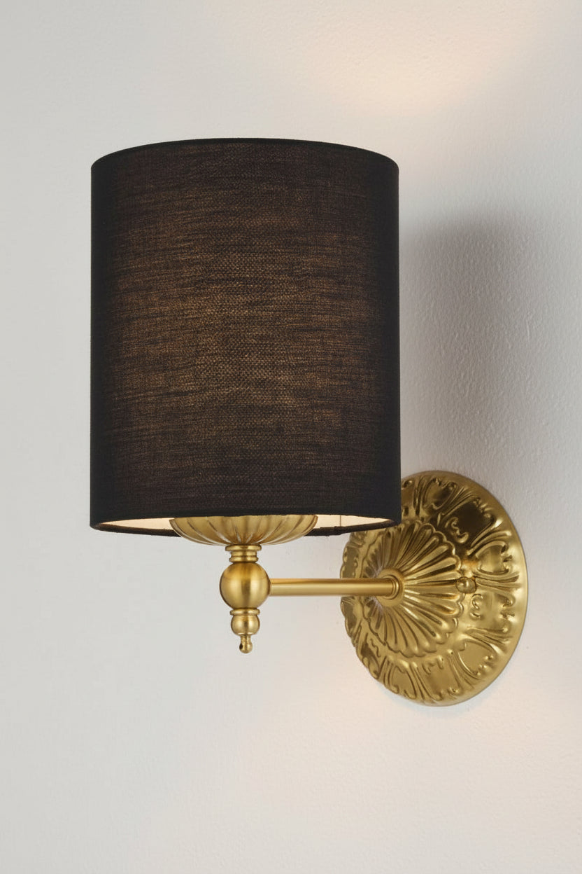 Illuminated antique gold finished wall sconce with heritage detailing and a black satin shade.  