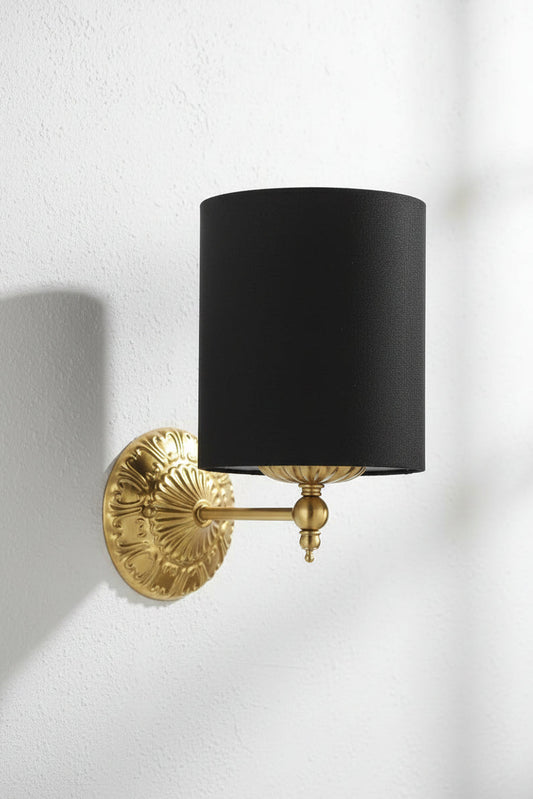 Antique gold wall sconce with detailing and a cylindrical black satin shade.