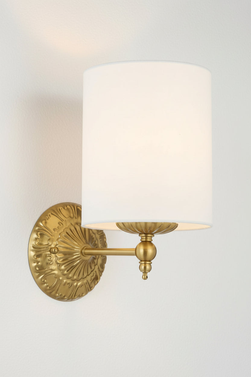 Illuminated antique gold finished wall sconce with heritage detailing and a ivory satin shade.  
