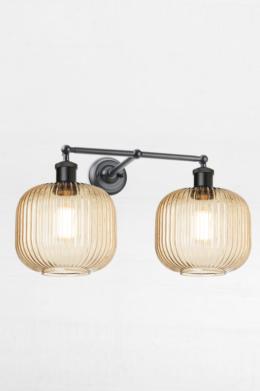 Two amber reeded glass open shades on a black double swivel wall sconce. 