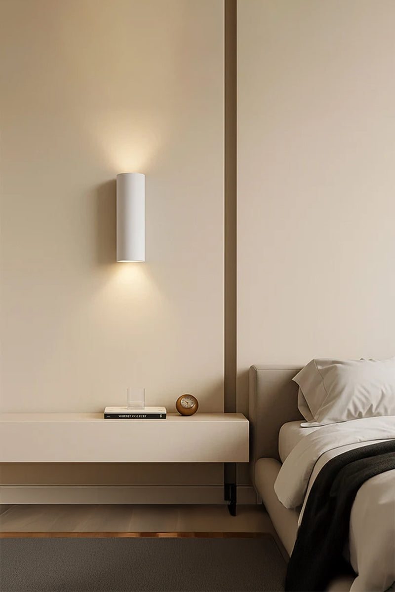 Maines Up Down Plaster Wall Sconce creating warm ambient up and down lighting beside a modern bedroom.