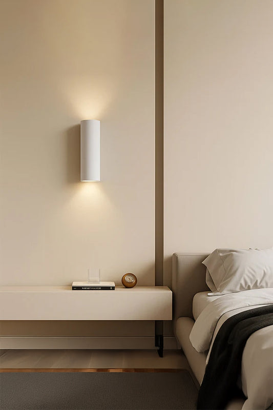 Maines Up Down Plaster Wall Sconce creating warm ambient up and down lighting beside a modern bedroom.