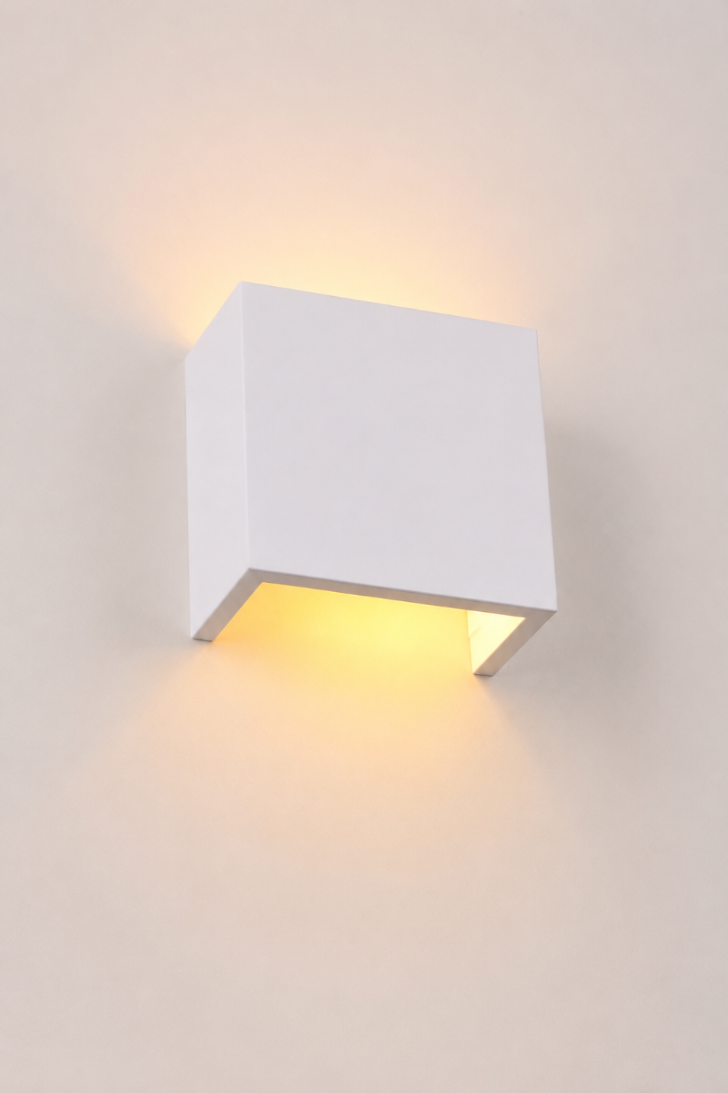 Close-up angled view of the illuminated Griffs Plaster Wall Sconce showing concealed up and down light output and minimalist square design.