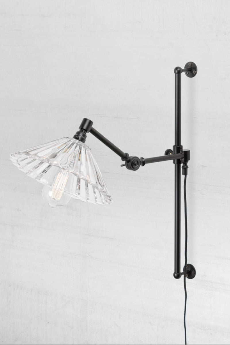 Black swing wall arm with wall plug and a clear glass pleated shade. 