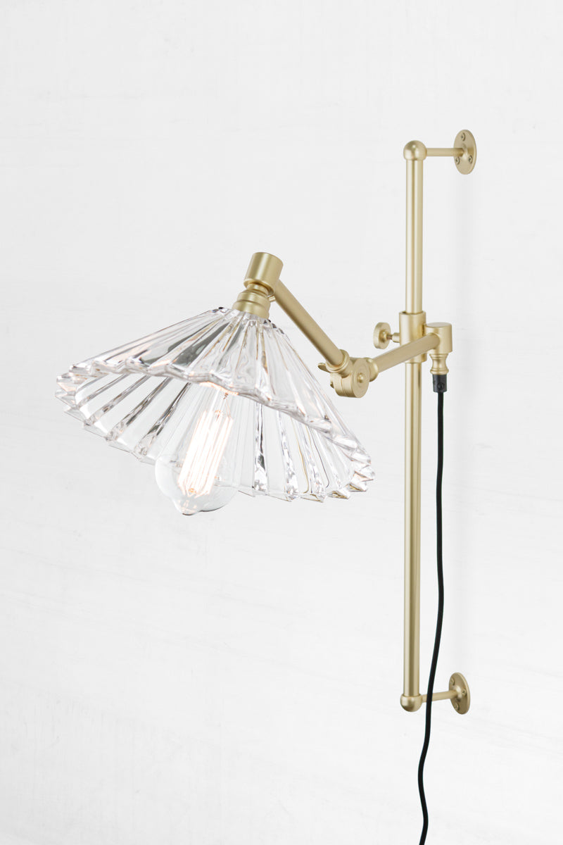 Clear glass pleated shade and gold/brass swing wall armfixture, paired with a teardrop bulb. 