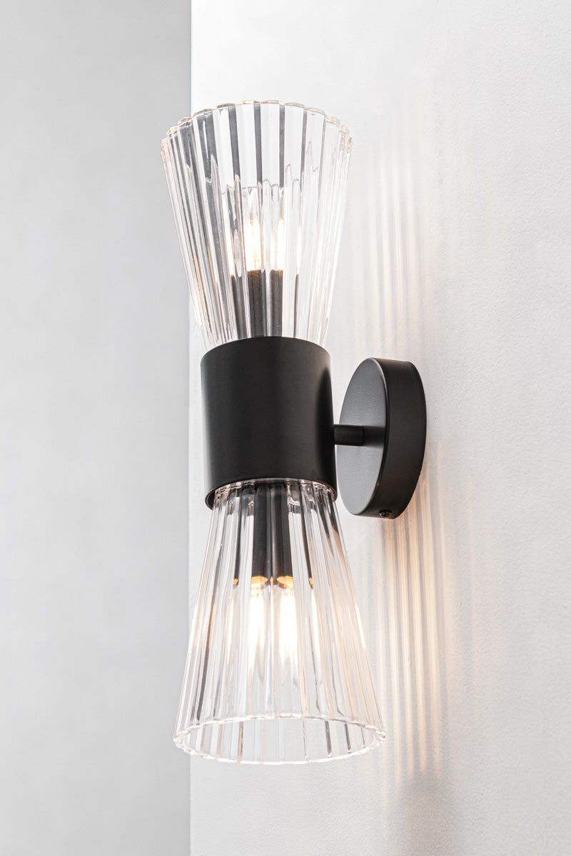 A wall-mounted sconce light fixture with clear ribbed glass shade. Slim 85mm projection keeps the profile tight against the wall