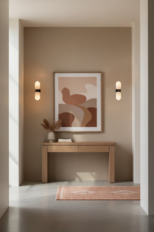 Two up/down wall sconce lights with opal galss and black hardware either side of artwork in a modern home entrance. 