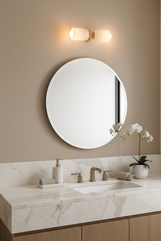 Gold/brass wall sconce with two opal glass shades over a bathroom mirror. 