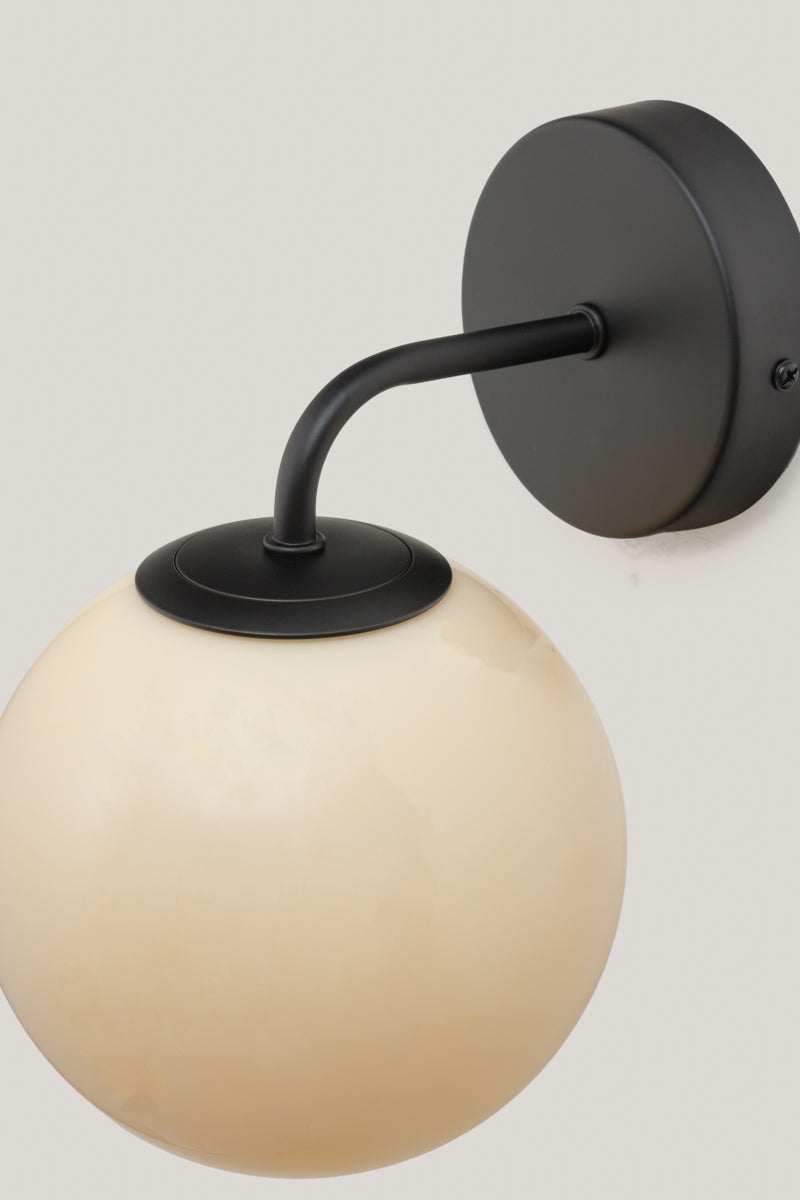 Boise Amber Glass Wall Light with black metal wall fixture and glossy amber globe shade shown unlit.