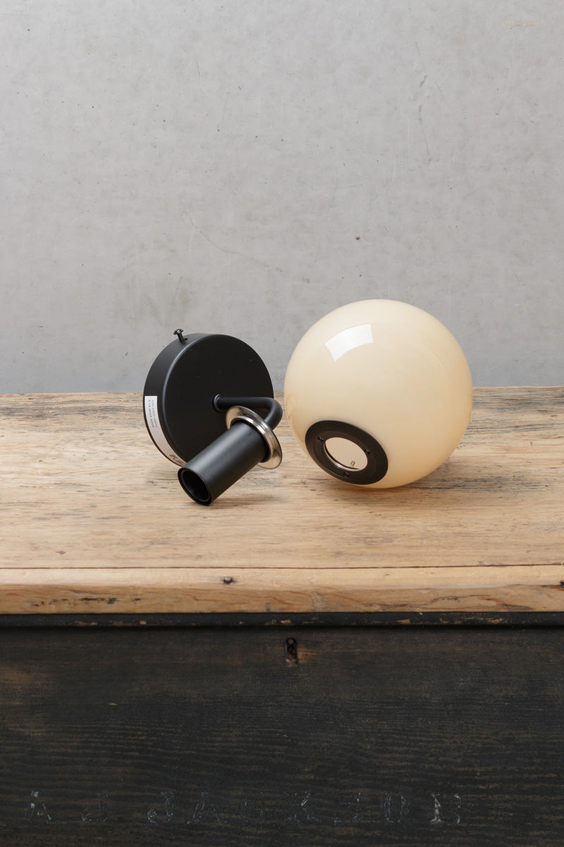 Boise Amber Glass Wall Light with black wall fixture and warm amber globe shade displayed on a timber surface.