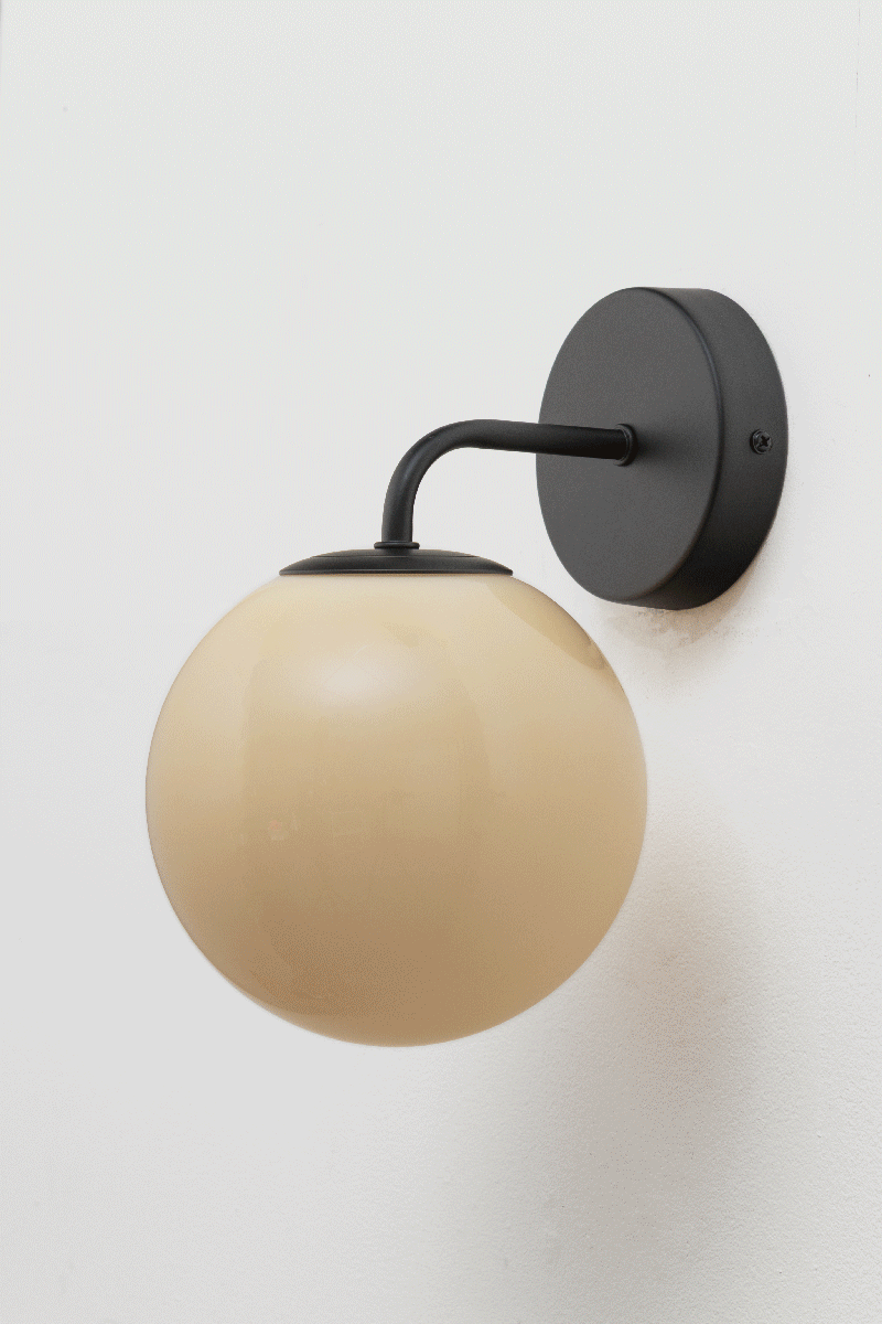 Boise Amber Glass Wall Light with black curved arm and round wall plate, featuring a warm amber glass ball shade.