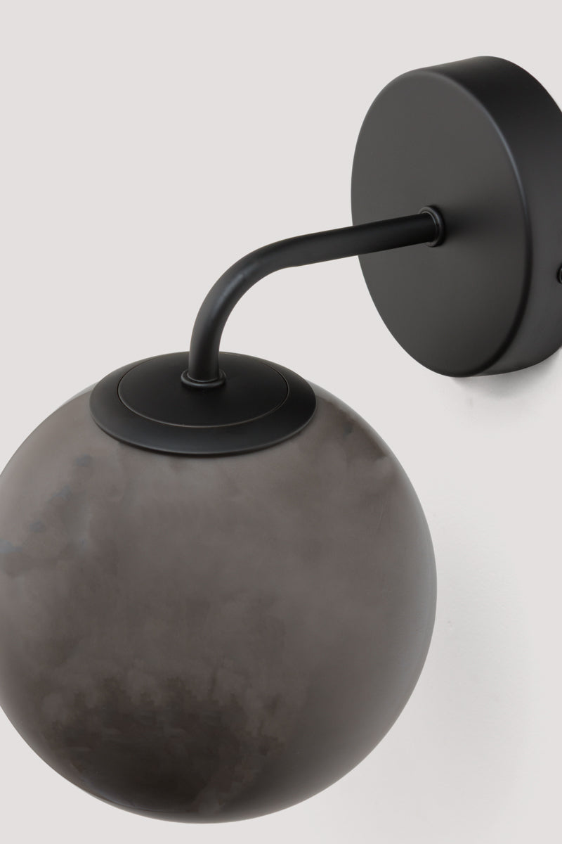 Boise Dark Grey Glass Wall Light with black wall fixture and soft smoked grey globe shade mounted on a white wall.