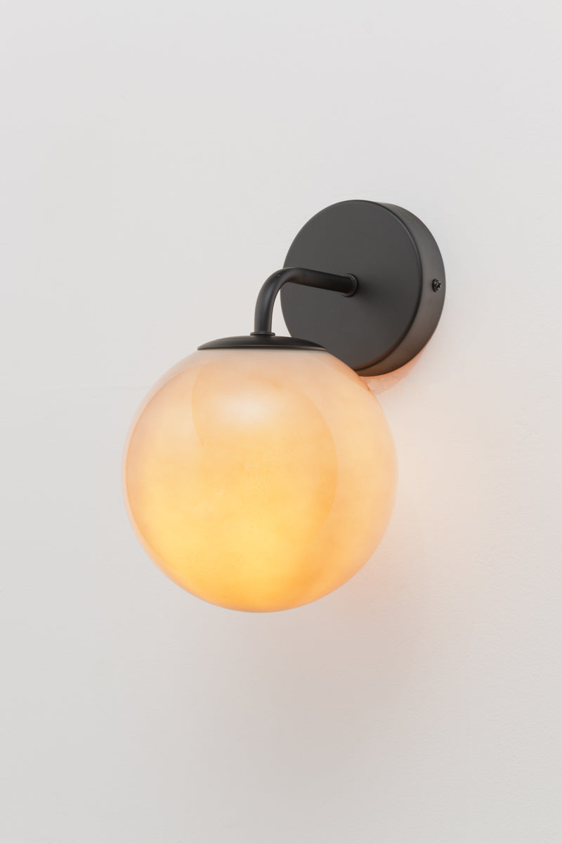 Boise light grey Glass Wall Light with glowing  light grey glass ball shade creating warm ambient illumination against a white wall.
