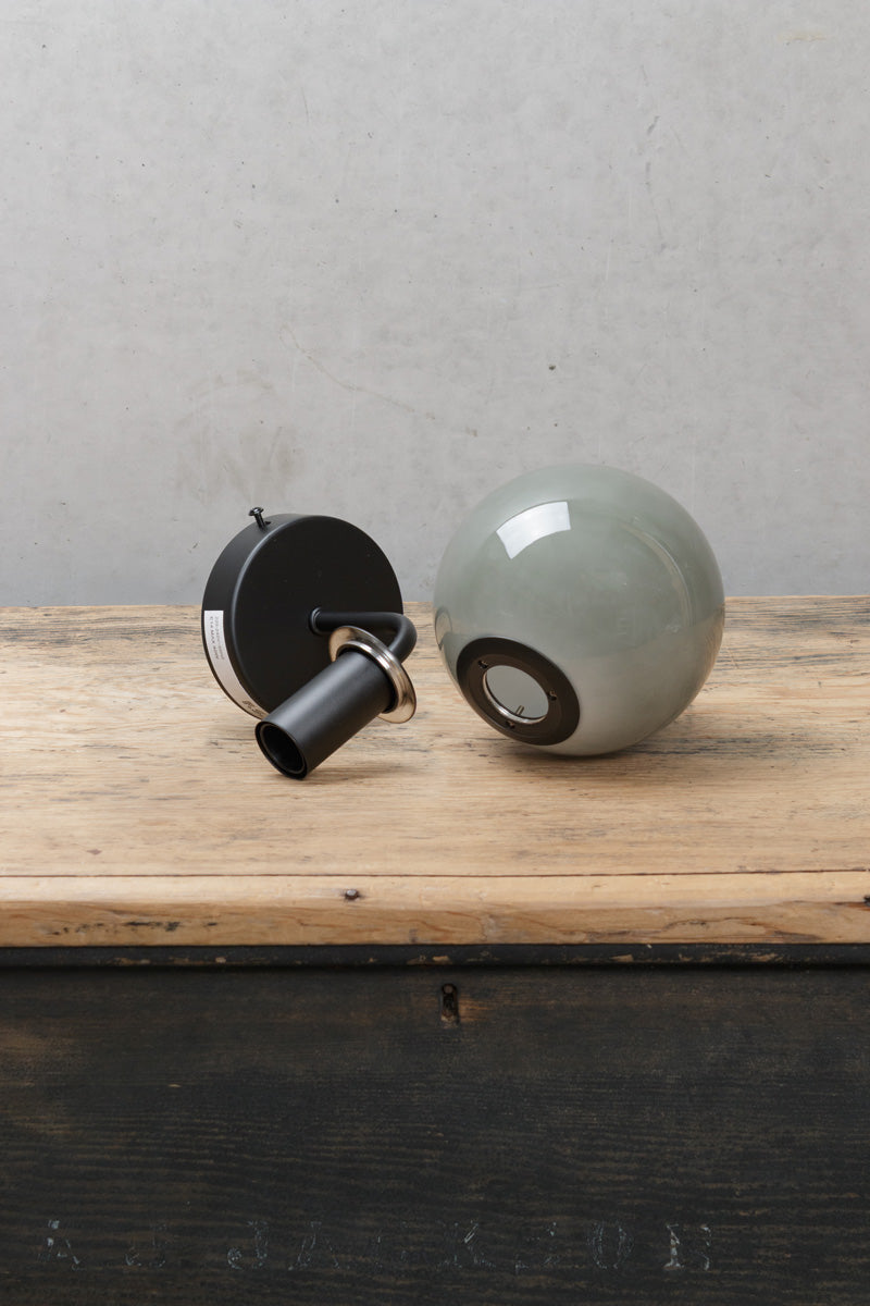 Boise Grey Glass Wall Light with black wall fixture and smoked grey globe shade displayed on a timber surface.