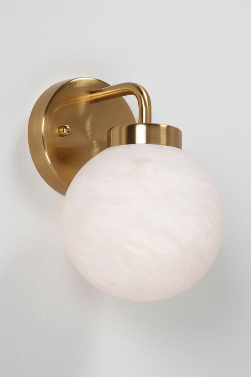 Brass finished wall light with opal alabaster finished spherical glass shade. 