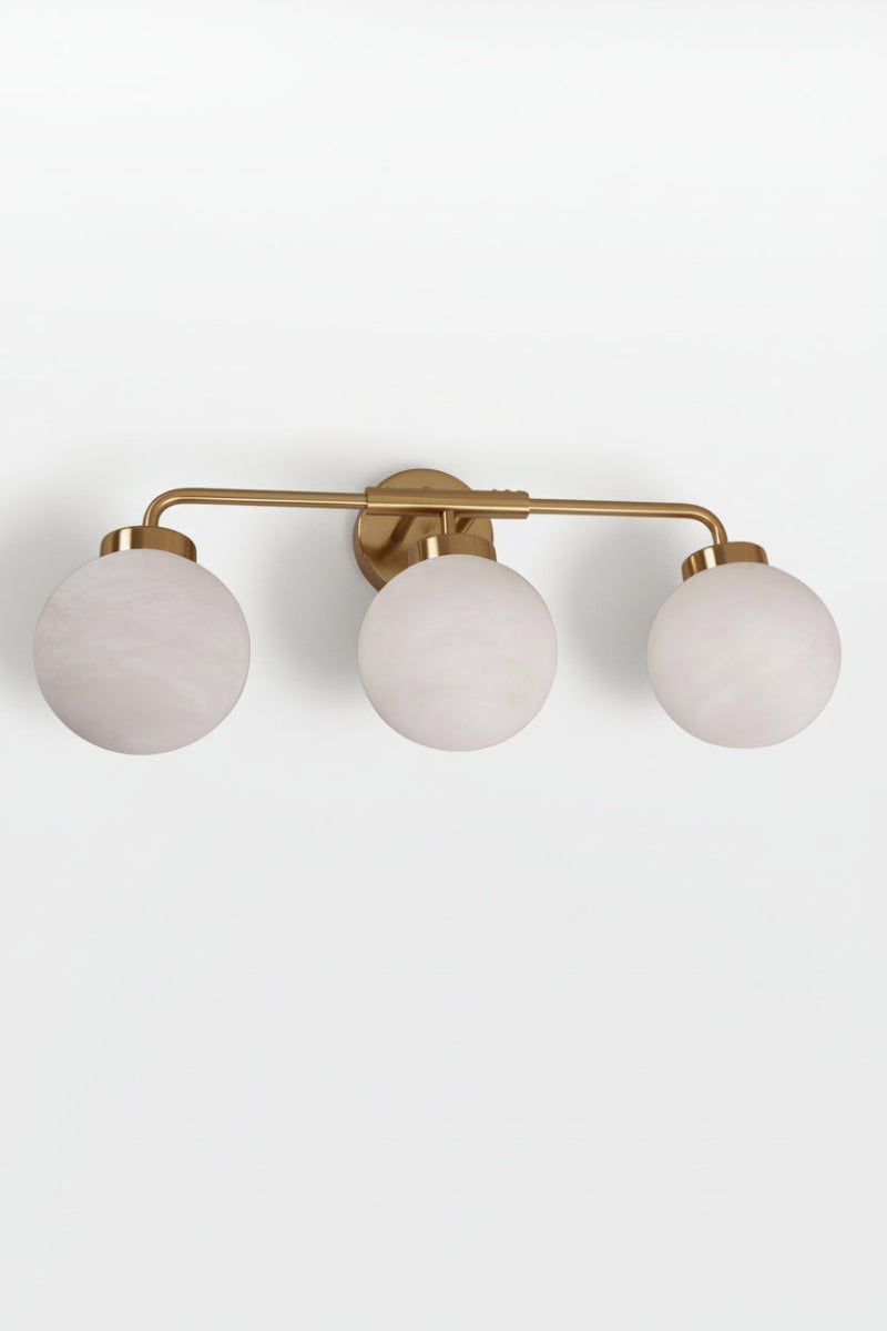 Brass finished triple wall light with opal alabaster finished spherical glass shades. 