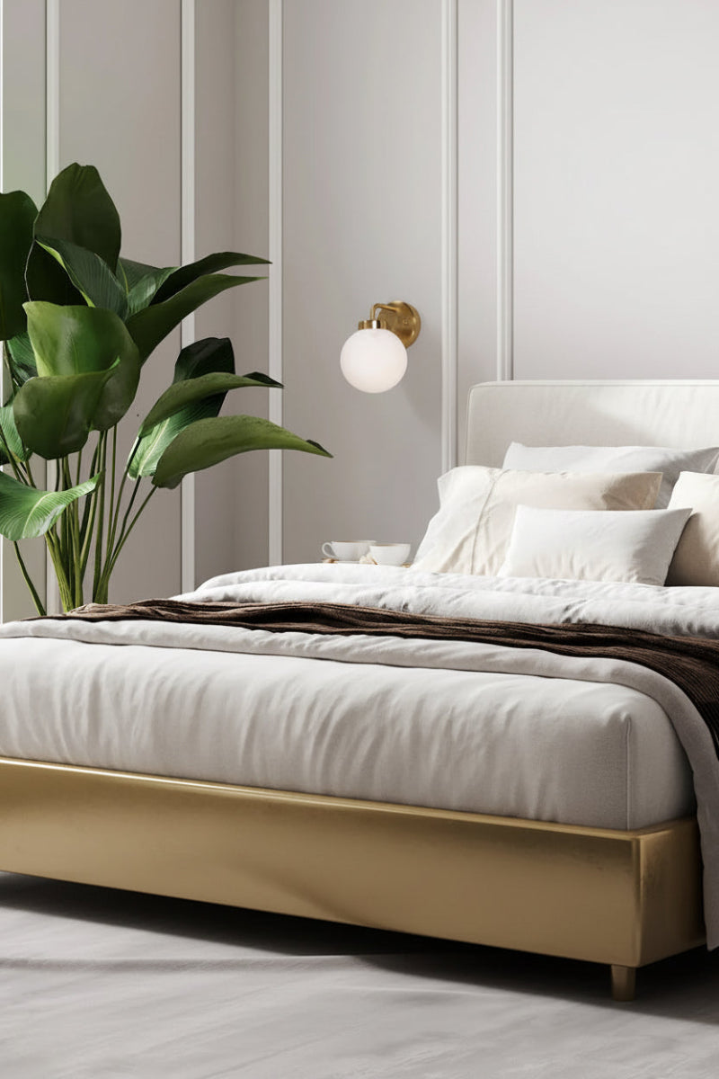 Brass finished wall sconce with sphereical glass shade as a bedside light