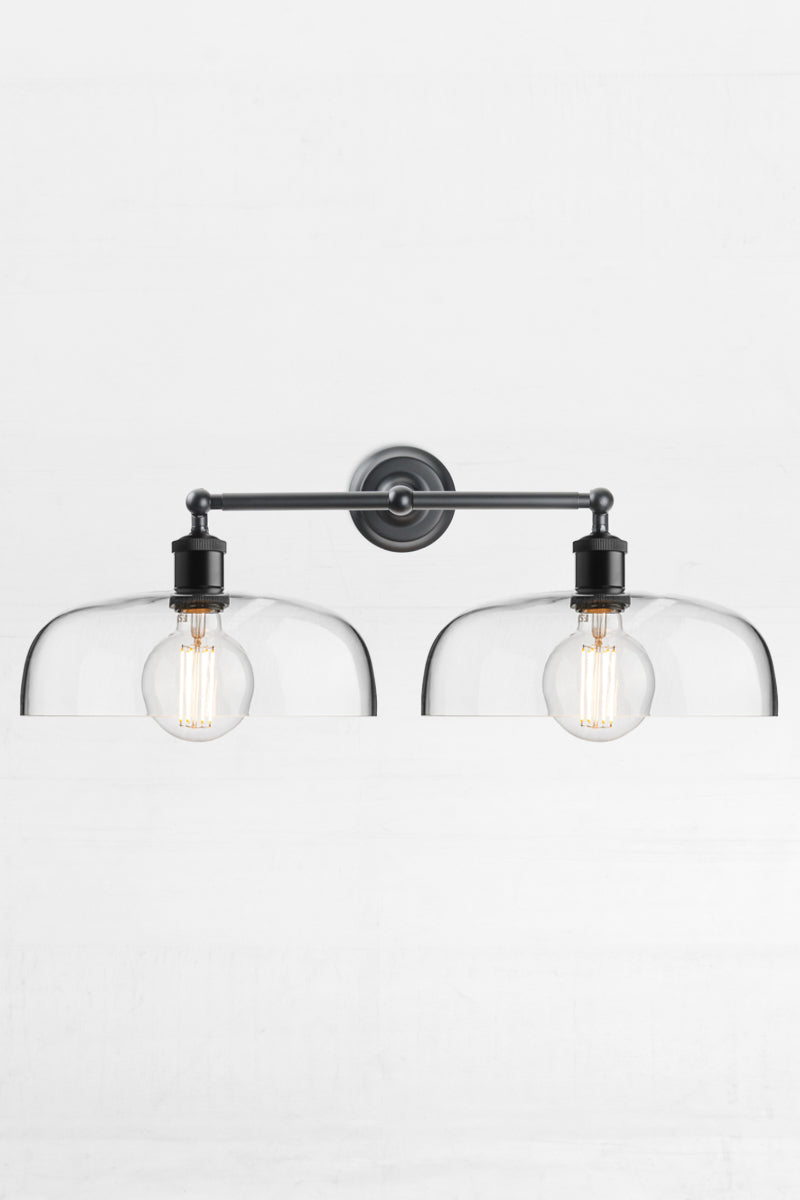 Black double swivel wall light with two smooth clear glass shades. 