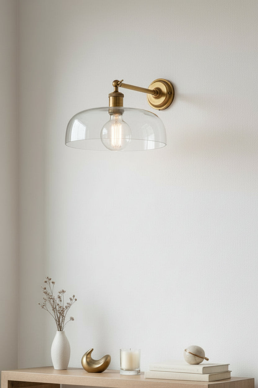 Clear dome glass shade on a gold swivel straight arm wall sconce over a table