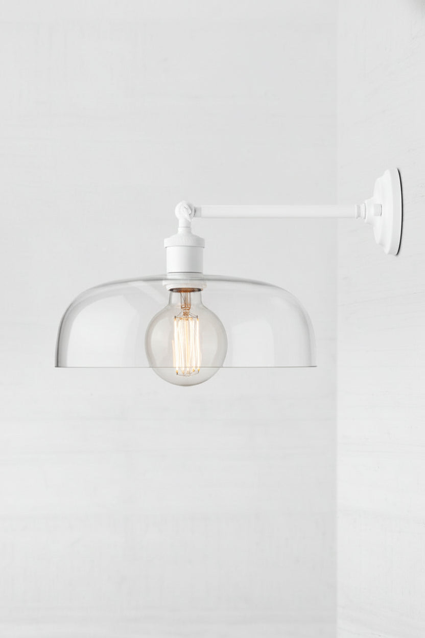 White long straight wall sconce with a large clear glass shade and round bulb
