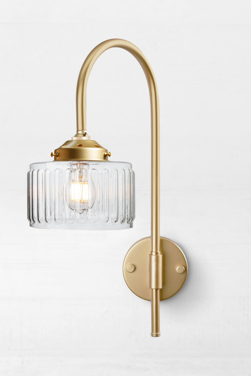 Gold/brass shepherds hook wall light paired with a clear glass shade. 