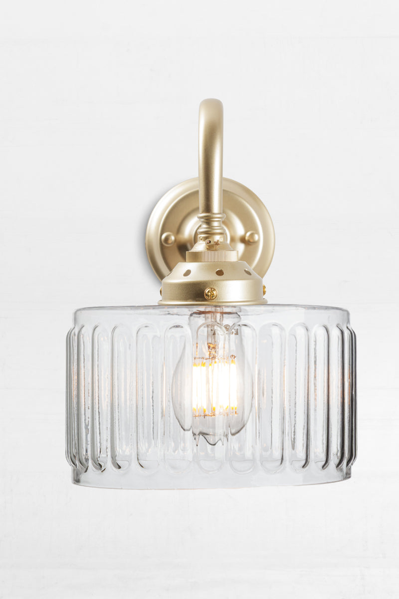 Clear glass shade with vintage fluted detailing on a gold/brass gooseneck wall sconce. 