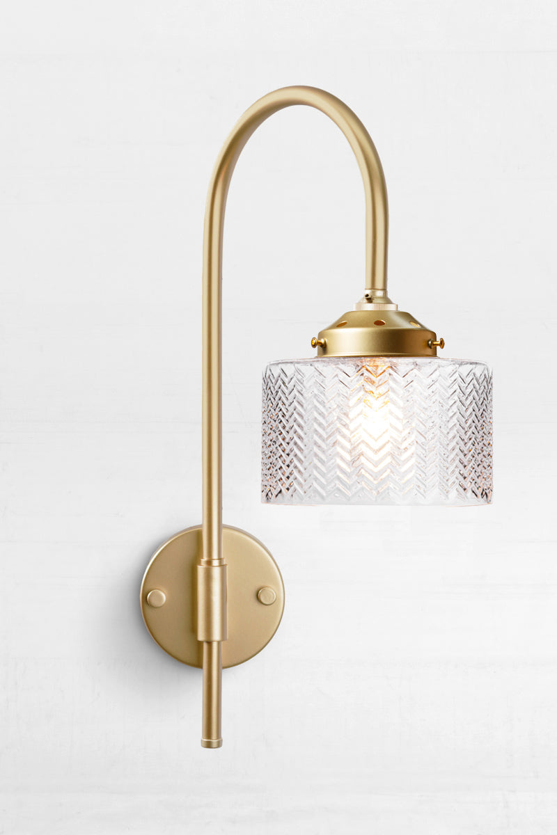 Gold/Brass shepherds hook wall sconce paired with a clear glass shade with a wavy chevron detail. 