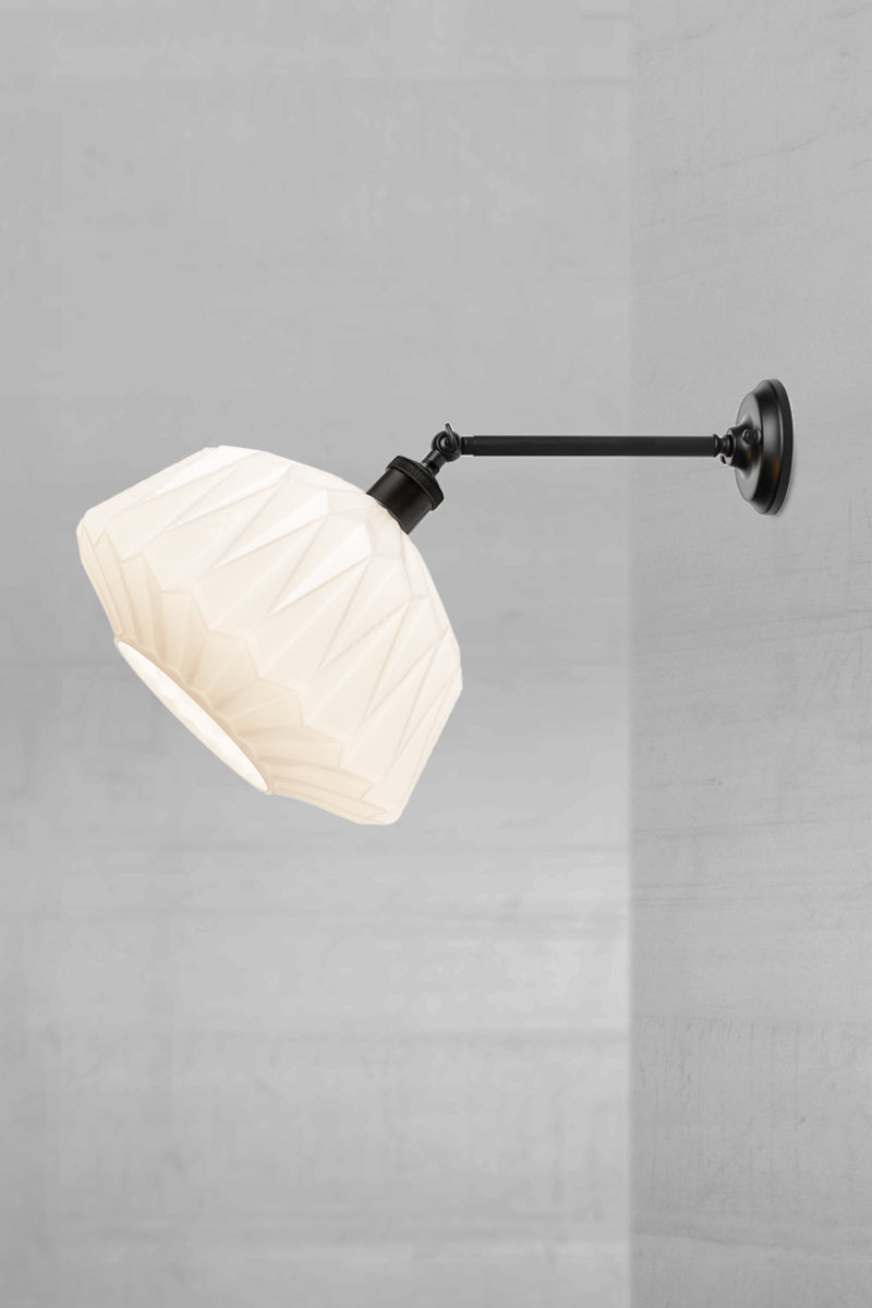 geometric opal glass shade on a long black straight arm wall sconce with swivel lampholder
